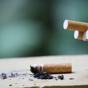Cigarette with ashes on surface, highlighting tobacco use and health risks.