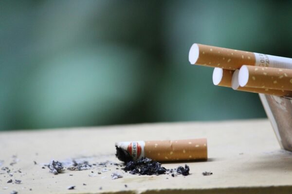 Cigarette with ashes on surface, highlighting tobacco use and health risks.