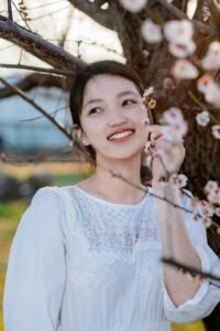 Smiling woman enjoys cherry blossoms in a springtime garden.